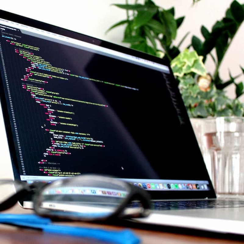 Glasses and computer with code in background